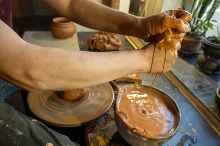 Closeup of potter makes pottery dishes on potter's wheel. Master and apprentice learning clay crafting.の写真素材