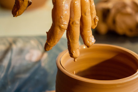 Hands of potter making a clay jug closeup.
