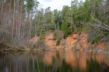The Echo cliff near river Salaca in Mazsalaca nature park. Beautiful natural formation. A naturally formed cave in the sandstone rock. A river flows along the cave. Devonian periodの写真素材