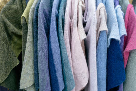 Women's multicolored knitted and crocheted sweaters, jackets hang on hangers in the store.の写真素材