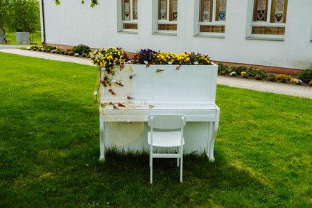 White piano and chairs with romantic decor in summer in garden. Decor for a wedding or a romantic dinner. Grand piano decorated with flowers stands outdoors. garden decor. rustic. celebration.の写真素材