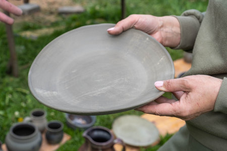 fired earthenware removed from the kiln. The woman looks at the outcome. Mugs, pots, plates and...
