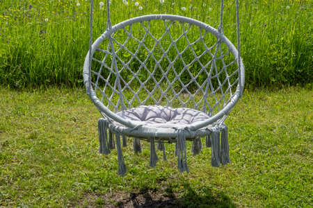 Decorative resting place in the form of a wicker swing suspended from a tree in an summer park.の写真素材