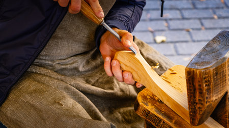 Hands carving spoon from wood, working with chisel close up. Process of making wooden spoon. wooden workshopの写真素材