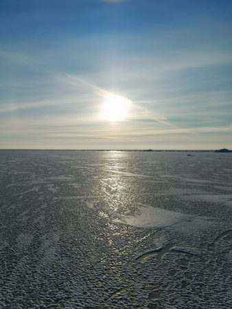 Sunset over the Baltic Sea in Latvia in winter. The coastline is covered with smooth ice. Frozen...