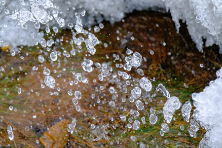 Water drops from a running spring outdoors in winter.