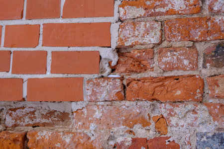 A fragment of an old red brick wall. Wall restoration site with new bricks.の写真素材