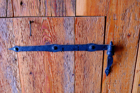 Old wooden door with rusted hinge in a farm house.