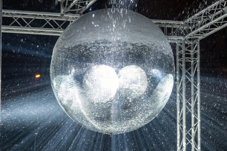 A large disc ball that reflects blue light. Disco symbol. Snowflake light rays.の写真素材