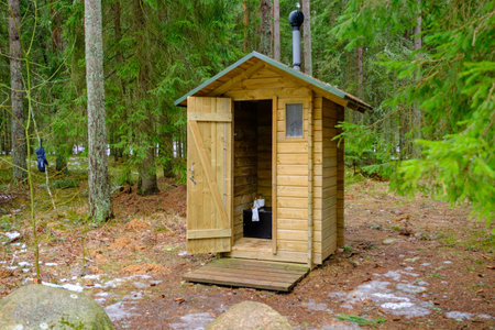 Wooden outdoor toilet in the forest with an open door. toilet paper rollの写真素材