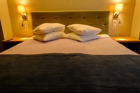 A symbol of a healthy night's sleep, a classic double bed made of solid wood with a bedside table and lighting. Marriage bed.の写真素材