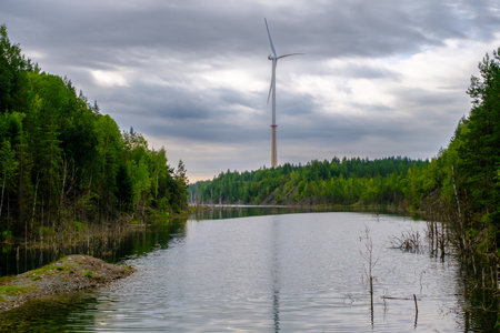 This is a former shale quarry with azure water and picturesque hills. Unlike the Narva shale settlement ponds. A dark autumn day. Estonia, Aidu quarry. A tall wind turbine in the distance.の写真素材