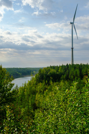 This is a former shale quarry with azure water and picturesque hills. Unlike the Narva shale settlement ponds. A dark autumn day. Estonia, Aidu quarry. A tall wind turbine in the distance.の写真素材