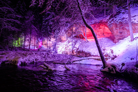 illuminated river at night in the forest. river in the forest in winter. it is snowing in the forest.の写真素材
