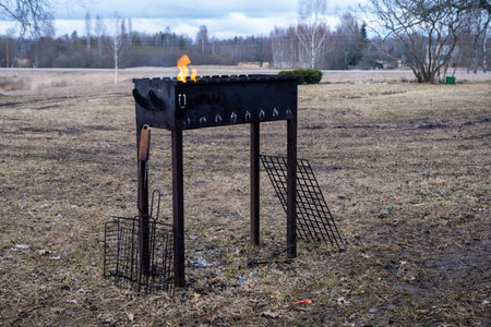 A barbecue grill stands in a field under the open sky