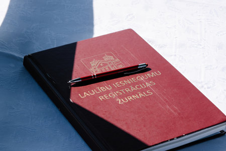Close-up of a wedding registration book with a pen placed on a white tablecloth, ready for signing during the ceremony.の写真素材