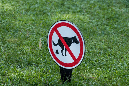 Close-up of a No Dog Fouling sign on a grassy lawn, prohibiting pet owners from allowing their dogs to poop in the area.の写真素材