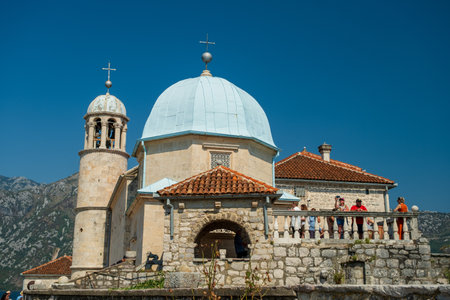 A close-up of a historic stone church with a blue dome, located on an island, featuring intricate architecture and tourist visitors.の写真素材