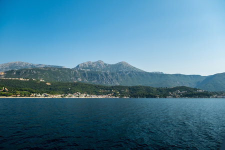 A serene coastal landscape with calm waters and a majestic mountainous backdrop, featuring small towns nestled along the shore under a clear sky.の写真素材