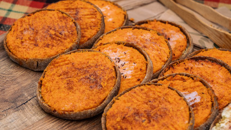 Authentic Latvian sklandrausis tarts with bright carrot filling and rye crust, beautifully arranged...