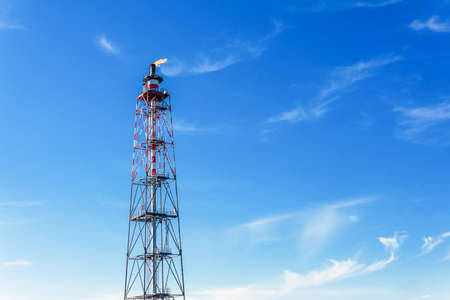 The flare pipe of the gas processing plant stands against the blue sky.の写真素材