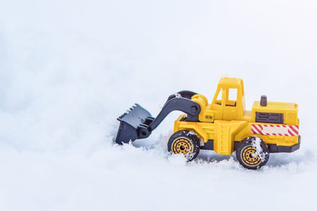 Yellow excavator removes snow on the road.の写真素材