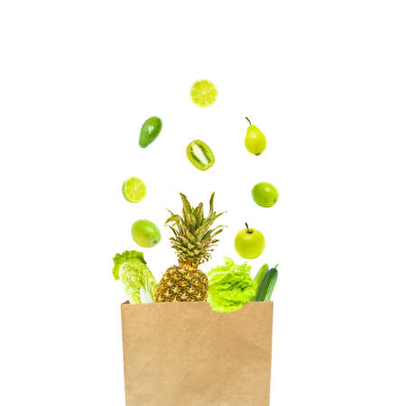 Isolate from green fruits and vegetables levitating in a paper bag. healthy eating.の写真素材