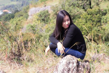 Thai woman with backpack sitting on cliffの写真素材
