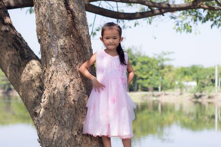 Little asian girl with tree near lagoonの写真素材