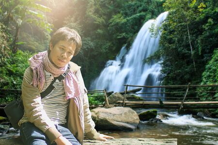 asian man with Pha dok siew waterfall in deep forest Chiang Mai Thailandの写真素材