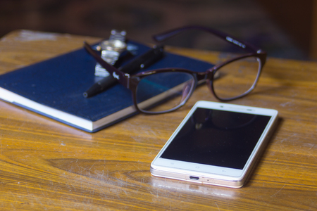 smart-phone Glasses book pen and watch on wood table for business or education conceptの写真素材