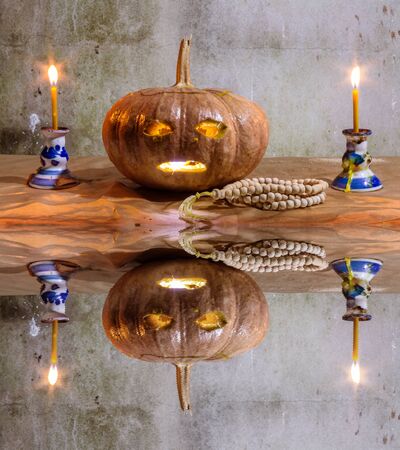 Halloween still life pumpkins candles and rosary  with water reflectionの写真素材