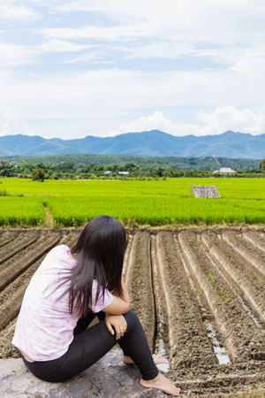 Asian woman lonely on rock with rice field with mountain in Thailand, Asiaの写真素材