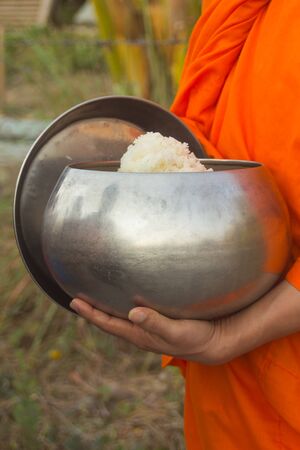 Thai monk with alms to a Buddhist monk on morningの写真素材