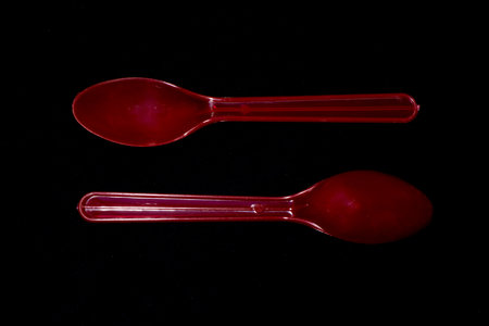 Red plastic spoon isolated on black backgroundの写真素材