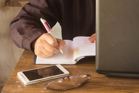 people write on book with  smart phone  and glass, and notebook on tableの写真素材