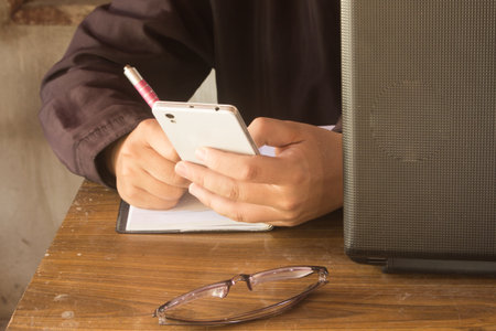 people write on book with  smart phone  and glass, and notebook on tableの写真素材