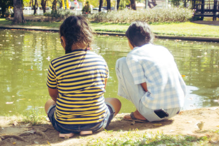 Two asia girl sit near water in the parkの写真素材