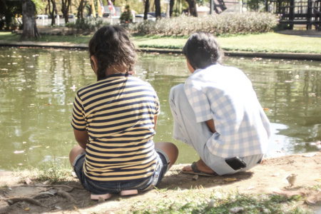 Two asia girl sit near water in the parkの写真素材