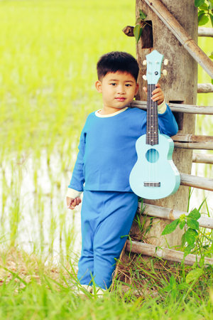 Poetrait asia boy with ukulele at green rice fieldの写真素材