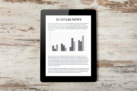 Tablet computer with business news on a screen on a background of woodの写真素材