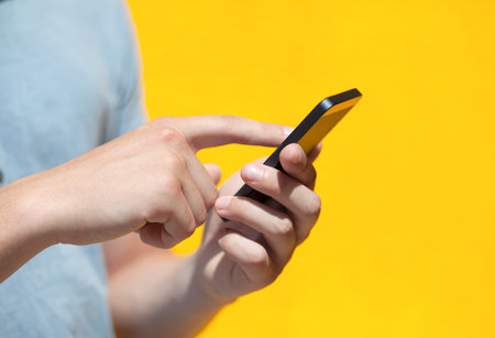 boy holding a phone and a touch screen for finger against a yellow wall