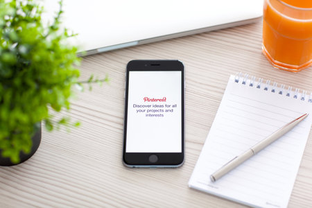 Alushta, Russia - October 24, 2014: Phone iPhone 6 Space Gray on the table with social Internet service Pinterest on the screen. iPhone 6 was created and developed by the Apple inc.のeditorial素材