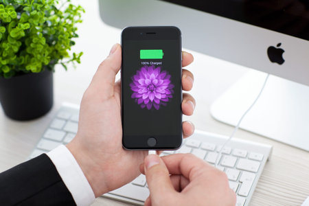 Alushta, Russia - November 3, 2014: Man holding a iPhone 6 Space Gray with battery icon on the...