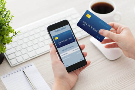 female hands holding phone with mobile wallet for online shopping over the desk