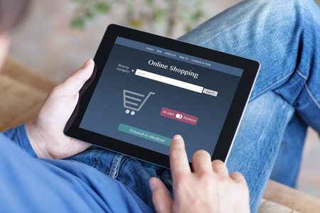 man sitting on the sofa and making online shoppind on a tabletの写真素材
