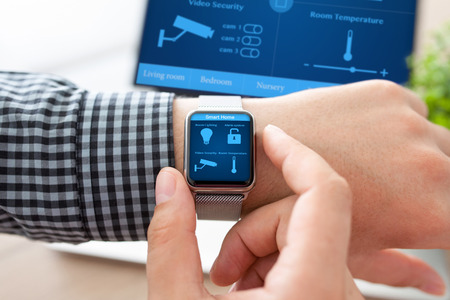 man hand in watch with program smart home on the screen against the background of computer