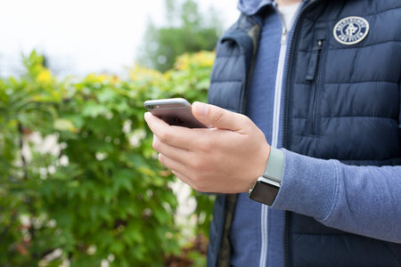 Alushta, Russia - October 13, 2015: Man hand with Apple Watch holding iPhone. Apple Watch was...