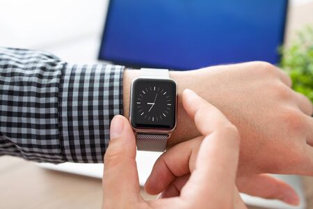 man hand holding smart Watch on the background of notebookの写真素材