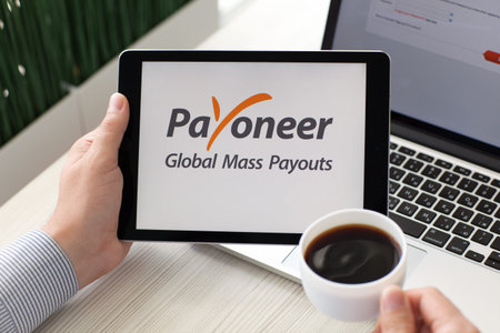 Alushta, Russia - September 3, 2016: Man holding a iPad Pro with payment system service Payoneer on...